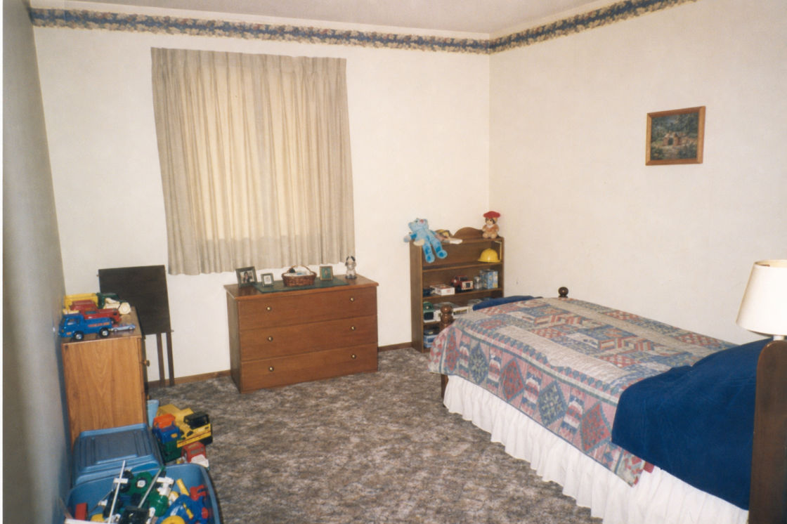 Before: an everyday 1990s childhood bedroom with a curtained window, wooden dresser and patterned carpet.