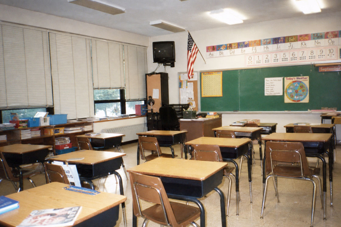Before: an empty 1990s elementary-school classroom with small desks, a chalkboard and fluorescent lights.