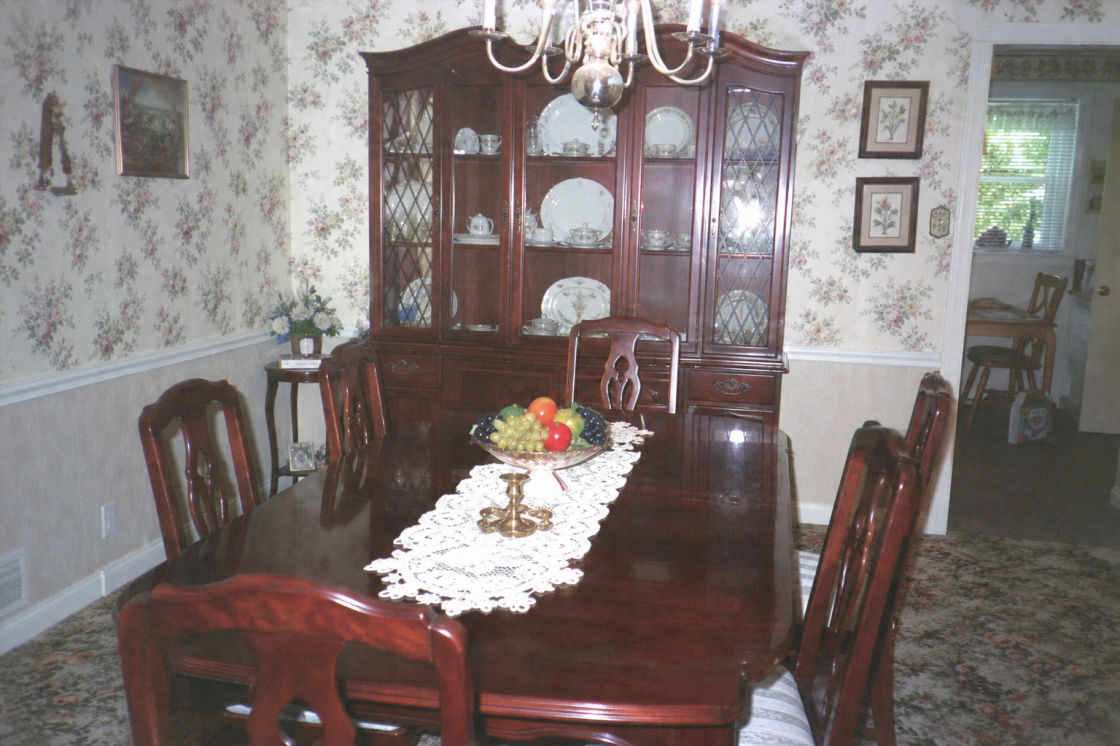 Before: a formal dining room with a long table, chairs and patterned wallpaper.