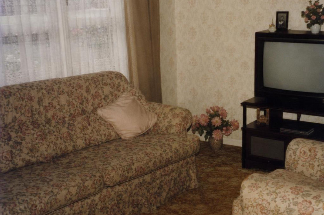 Before: a suburban living room with a sofa, side table and curtained window.