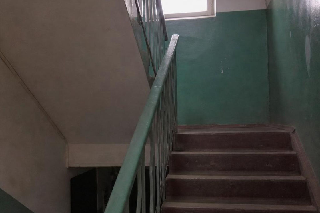 Before: a concrete back stairwell with metal railings and painted steps.